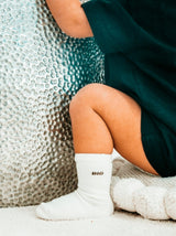 Bébé joyeux portant des chaussettes bébé beige confortables ornées de l'adorable message "Big Amor". Qualité supérieure, fabriquées en France.