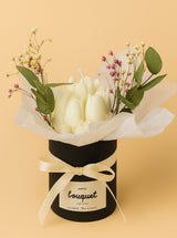 Bougie sculptée en bouquet dans pot noir avec fleurs séchées et eucalyptus